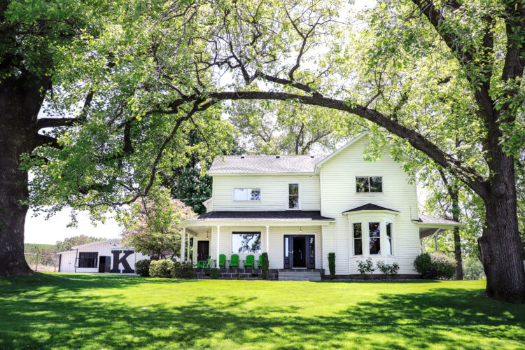 The original K Vintners farmhouse near Phil Lane Vineyard, is seen, with trees and grass and a large black 'K'